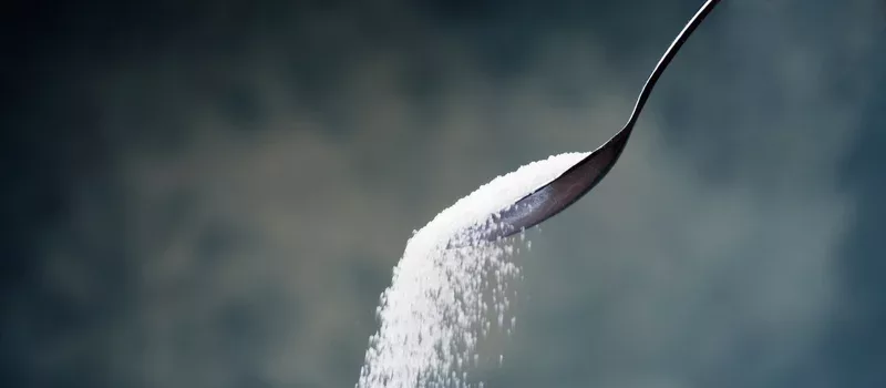 Adding sugar with a spoon.