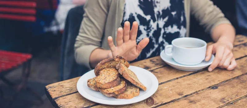 Young woman on gluten free diet is saying no thanks to toast in a cafe